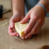 Skilled hands molding a bar of soap with natural ingredients visible